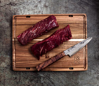 raw onglet steak on wood board